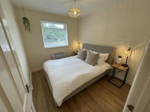 a bedroom with a bed with white sheets and a window at Charming 2-Bed Apartment in Danbury essex in Chelmsford