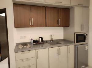 a kitchen with white cabinets and a sink and a microwave at Kyan Park Abha Hotel in Abha +11 photos