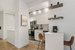 a white kitchen with a counter and chairs in it at Simple and Cozy Studio Apartment- Chestnut 04D in Chicago
