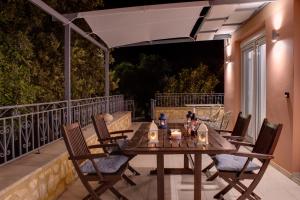 a wooden table and chairs on a balcony at night at Elysian Rose Residence in Rethymno