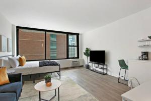 a living room with a couch and a large window at Serene & Completely Furnished Studio Apartment- Chestnut 14F in Chicago