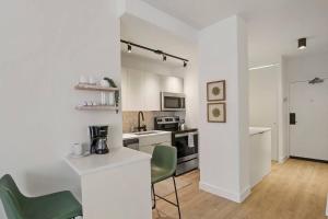a white kitchen with green chairs and a counter at Serene & Completely Furnished Studio Apartment- Chestnut 14F in Chicago