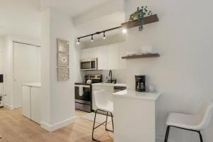 a white kitchen with white chairs and a counter at Inviting Fully Furnished Studio Perfect Location- Chestnut 02D in Chicago