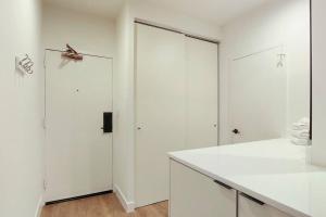 a white kitchen with white cabinets and a large door at Inviting Fully Furnished Studio Perfect Location- Chestnut 02D in Chicago