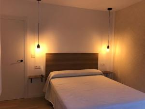 1 dormitorio con 1 cama con 2 luces encima en Trasariz Suites 2 en Vimianzo