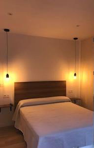 1 dormitorio con 1 cama blanca y 2 luces en Trasariz Suites 2 en Vimianzo