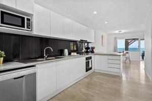 uma cozinha branca com um lavatório e um micro-ondas em Sea Breeze Two Bedroom Apartment em Redcliffe