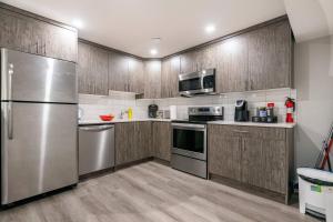 Una cocina con electrodomésticos de acero inoxidable y gabinetes de madera. en Luxurious Comfortable Suite, en Airdrie