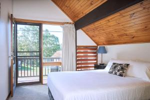 a bedroom with a large bed and a balcony at Wandin Valley Estate in Lovedale