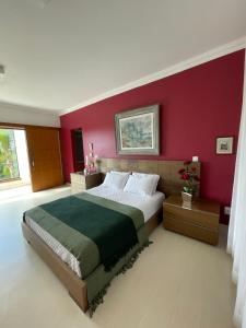 una camera da letto con un letto grande con una parete rossa di Village Recanto Splendory - Sítio com lazer completo e privativo perto de BH a Prudente de Morais Altre 26 foto