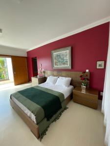 1 dormitorio con 1 cama grande y pared roja en Village Recanto Splendory, en Prudente de Morais