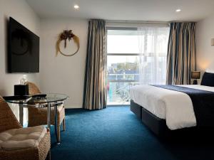 a hotel room with a bed and a table and a window at Beaches Nelson in Nelson