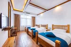 a bedroom with three beds and a flat screen tv at Guihua Road 106th Hostel in Zhangjiajie
