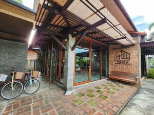 a building with a bike parked outside of it at ท่ามะโอบูทีคโฮมสเตย์ Tha Ma-O Bouteak Homestay in Lampang