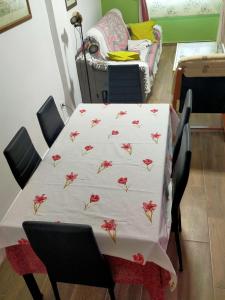 una mesa con un mantel blanco con flores rojas. en Apto a 5 min a pie de la playa, en Málaga