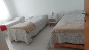 a bedroom with two beds and a table and a window at Duplex Bosch in Neuquén