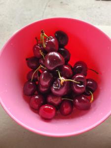 a pink bowl full of cherries on a table at Finca san benito in Puerto Madryn