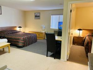 a hotel room with a bedroom with a desk and a bed at Fraser Bridge Inn in Quesnel