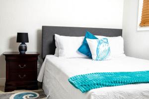 a bed with blue and white pillows and a night stand at Sheer Bliss BeachView Apt #2 in Exuma Harbour Estates