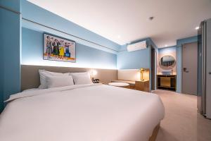 a bedroom with a large white bed and blue walls at Wonju Hotel Ippda in Wonju