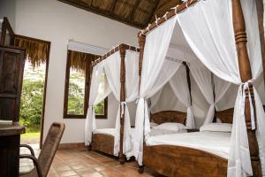 1 dormitorio con cama con dosel y cortinas blancas en Hotel Reserva de Piedemonte en Villavicencio