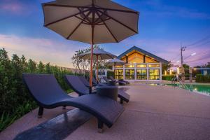 a group of chairs and an umbrella next to a pool at MOST Family 40 Ubon in Ubon Ratchathani