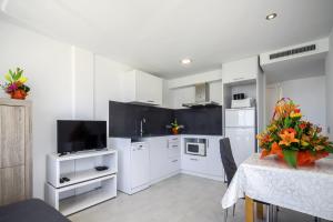 a kitchen with white cabinets and a table with a vase of flowers at Inmosantos Oasis F5 in Roses