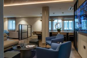 a living room with a tv and blue chairs at The Brunei Hotel in Bandar Seri Begawan