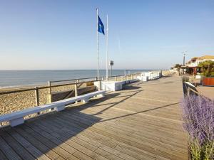a boardwalk leading to the beach with a flag at Appartement cosy à 100m de la plage avec mezzanine, terrasse et parking privatif - FR-1-194-263 in La Tranche-sur-Mer +6 photos