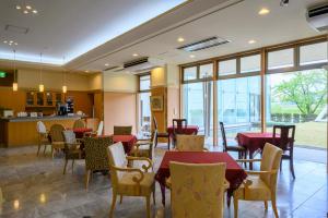 um restaurante com mesas e cadeiras vermelhas e janelas em Hotel Symphony Annex Sagae Onsen em Sagae