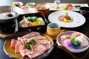 une table avec des assiettes de nourriture sur une table dans l'établissement Hotel Symphony Annex Sagae Onsen, à Sagae