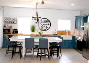 a kitchen with blue cabinets and a white table and chairs at Riverbend Ranch for Family Fun on Smith Lake! Dogs welcome! in Crane Hill