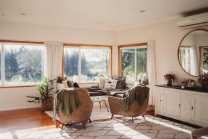 sala de estar con sofá, sillas y ventanas en Paradise Valley Lodge en Rotorua