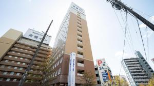 Un edificio alto con una grúa delante. en Toyoko Inn Mikawa anjo eki Shinkansen Minami guchi No 2, en Anjomachi