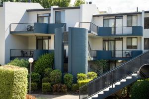 an apartment building with blue balconies and bushes at Manuka Park Serviced Apartments in Canberra