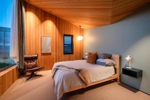 ワナカにあるHideaway on Warren by Sotheby's Luxury Rental Homesのベッドと椅子と窓のある寝室