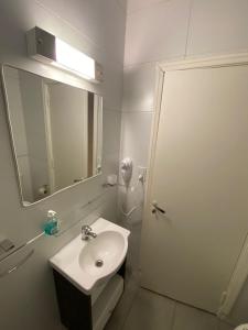a white bathroom with a sink and a mirror at Depto céntrico remodelado in Mar del Plata