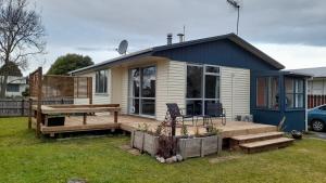 ein kleines Haus mit einer Holzterrasse im Hof in der Unterkunft Pihanga Vista Cottage in Turangi