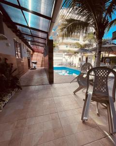 a patio with chairs and a pool in a building at Flamingo Beach Pousada in Cabo Frio