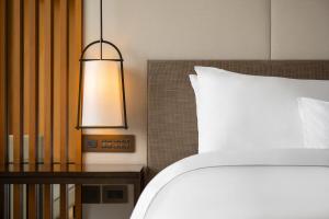 大渓区にあるザ ウェスティン ダーシー リゾート タオユェンのベッドルーム1室(ベッド1台付)、テーブルの横のランプが備わります。