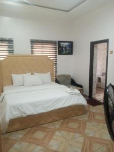 a bedroom with a large bed and a chair at Delad Hotel and Suites in Ibadan