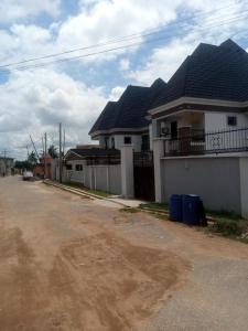 a white house with black roofs and a dirt road at Delad Hotel and Suites in Ibadan