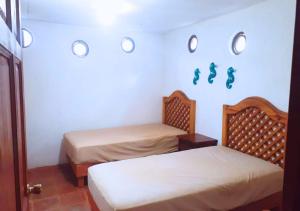 two twin beds in a room with a wall with footprints on it at Casa Andivi, Placer sin fin in San Pedro Pochutla