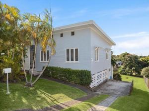 een wit huis met een palmboom in de tuin bij 15 Seaview Terrace Moffat Beach QLD in Caloundra