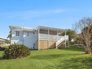 een wit huis met een veranda en een grote tuin bij 15 Seaview Terrace Moffat Beach QLD in Caloundra