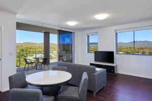 a living room with a table and chairs and a tv at Two bedroom Apartment in Robina Center in Gold Coast