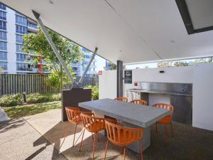 a kitchen with a table and orange chairs at Two bedroom Apartment in Robina Center in Gold Coast