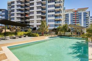 a swimming pool in front of a large apartment building at Two bedroom Apartment in Robina Center in Gold Coast