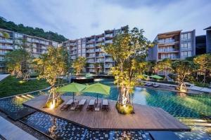 uma piscina com cadeiras e guarda-sóis num hotel em Deluna 23degree by The valley khao yai em Pak Chong