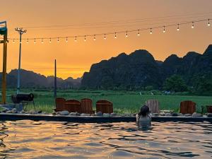 a woman is sitting in a swimming pool at Tam Coc Windy Fields in Ninh Binh